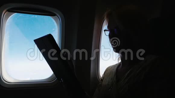 一个女人坐飞机在平板电脑上读东西侧视图视频的预览图