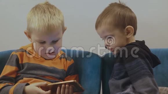 可爱的蹒跚学步的男孩坐在椅子上使用智能手机4K视频的预览图