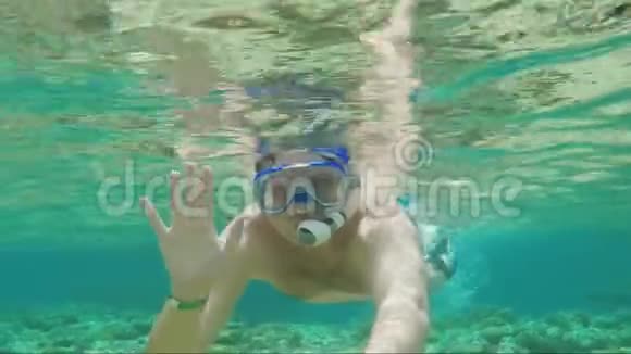 一个戴着烟斗面具的快乐潜水员看着相机挥动他的手水下视频中一个伟大的假期视频的预览图