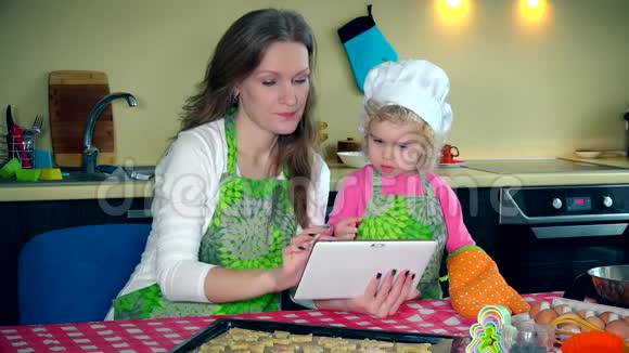 母亲和女儿在数码平板电脑上做饼干视频的预览图