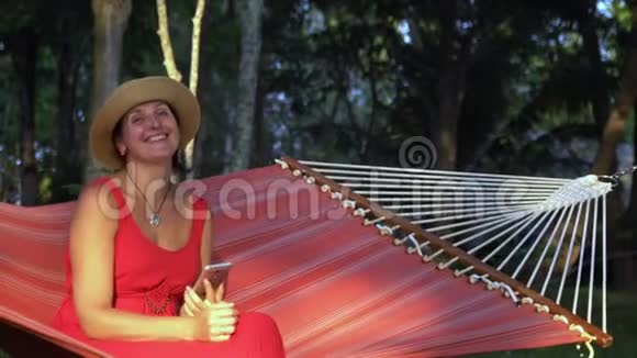 穿着红色衣服的女人坐在热带花园的红色吊床上普夸克岛的太阳能女人坐在视频的预览图