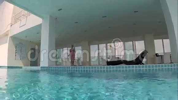 快乐美丽的年轻女子跳进游泳池假期暑期时间操作摄像机视频的预览图