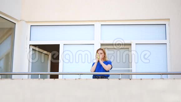 一个年轻的女人走到阳台上环顾四周她微笑着凝视着远方手里拿着一个杯子视频的预览图
