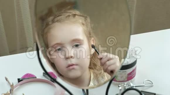 头发红的小女孩把阴影放在眼皮上照镜子化妆脸时尚风格化妆品视频的预览图