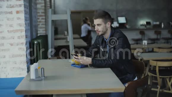 年轻的帅哥在4K咖啡馆的智能手机上聊天视频的预览图