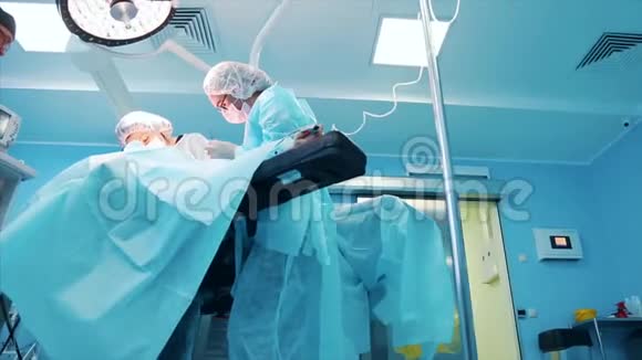 一组专业外科医生对医院手术室的一名病人进行侵入性手术外科医生使用和视频的预览图