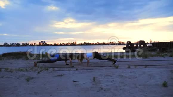 美丽苗条的年轻女性从事健身表演力量练习黎明时分沿着沙漠码头视频的预览图