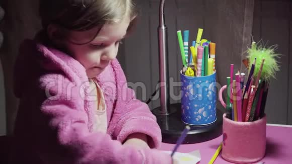 穿着粉红色浴袍的漂亮小女孩正在用彩色铅笔画插图视频的预览图