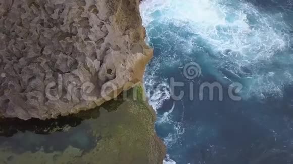 天使Billabong自然游泳池在热带岛屿的岩壁上发生了大的蓝海波浪4K旅行录像努沙视频的预览图