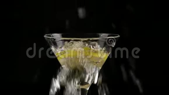 一片柠檬被扔进一个杯子里酒精鸡尾酒在黑暗的背景下慢动作视频的预览图