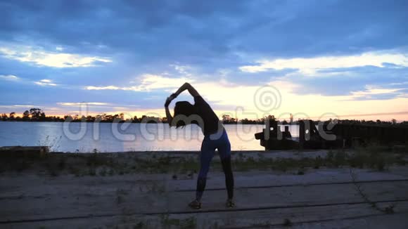 美丽苗条的年轻女子从事健身表演力量练习黎明时分沿着沙漠码头视频的预览图