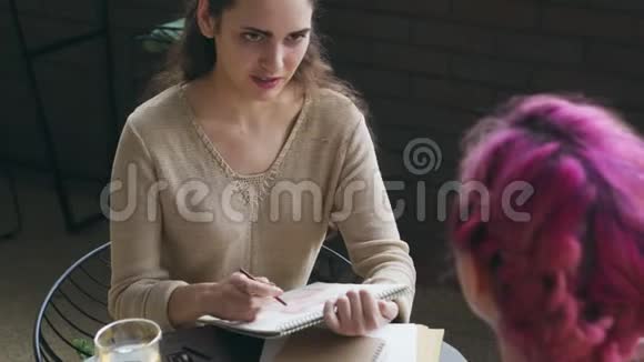 女人在咖啡馆画素描和朋友聊天视频的预览图