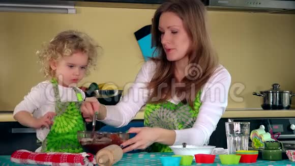妈妈微笑着辅导女儿准备厨房自制蛋糕的面团视频的预览图
