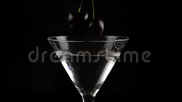 樱桃被扔进一个杯子里酒精鸡尾酒在黑暗的背景下准备鸡尾酒和派对概念慢慢慢慢视频的预览图