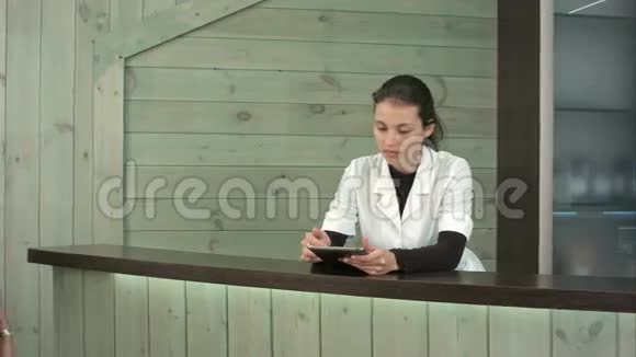 微笑水疗经理与平板电脑问候女客户在接待处视频的预览图