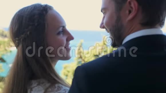 在海边的背景下新娘和新郎站在酒店的阳台上视频的预览图