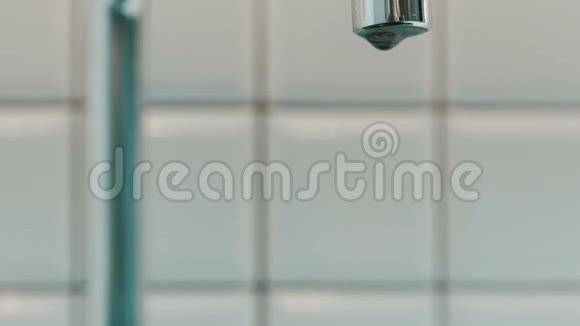 清洁的水从室内浴室的金属水龙头滴下来视频的预览图