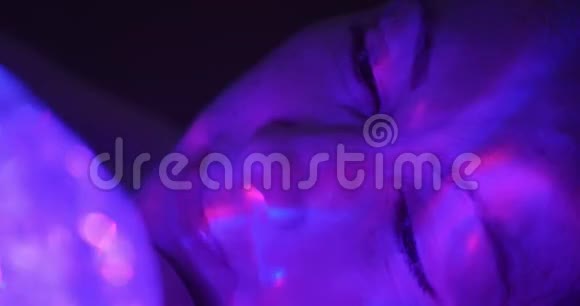 女孩看着充满水凝胶发光的彩色球的手电筒视频的预览图
