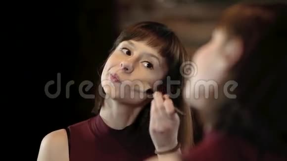 年轻女子在镜子前化妆满脸背景模糊漂亮的年轻女孩正在化妆青年视频的预览图