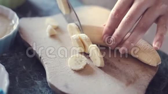 女性手在木板上切香蕉视频的预览图