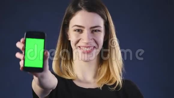 专注于手机年轻女子的手显示空白智能手机屏幕隔离在绿色背景和指向视频的预览图
