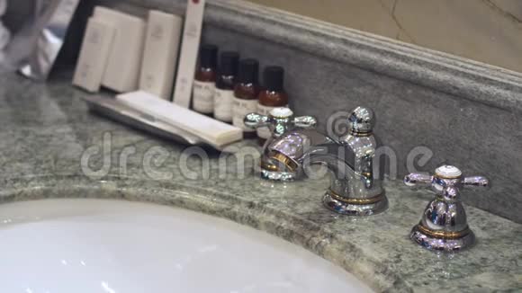 女人转动浴室的水龙头和洗手池视频的预览图