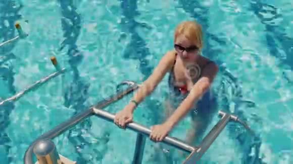 在游泳池里训练你的身体一位身穿泳装的年轻女子正护送着在泳池里进行模拟训练视频的预览图