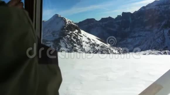 从飞机驾驶舱拍摄的飞越白雪覆盖的高山的照片视频的预览图