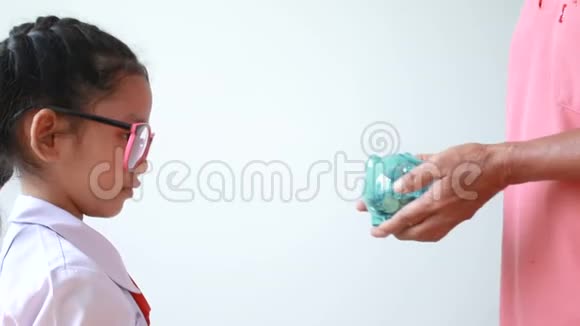 老奶奶的手把清晰的储蓄罐送给亚洲小女孩而不是白色背景的比喻为教育省钱视频的预览图