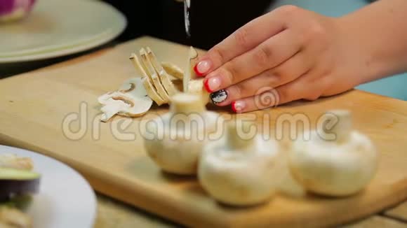 一个女人用刀子在木板上把香菜蘑菇切成薄片视频的预览图