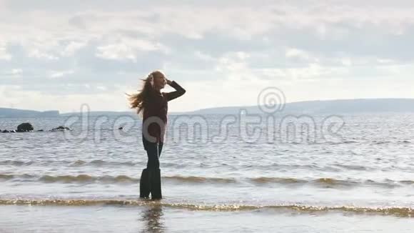 一个年轻的女孩站在河里穿着橡胶靴子傻笑视频的预览图