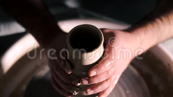 人们在陶轮上做锅的俯视图波特用专业工具塑造粘土制品花瓶或杯子视频的预览图