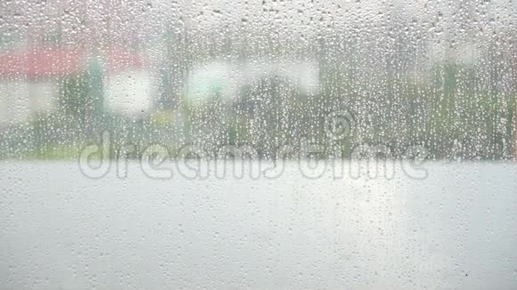 潮湿的窗户玻璃阴天模糊的城市背景下的窗户玻璃表面的雨滴视频的预览图