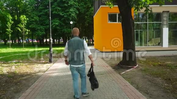 穿着牛仔裤衣服手里拿着包的漂亮年轻人走在街上视频的预览图