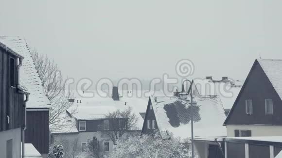 家庭房屋的雪屋顶山镇街道村雪灾视频的预览图