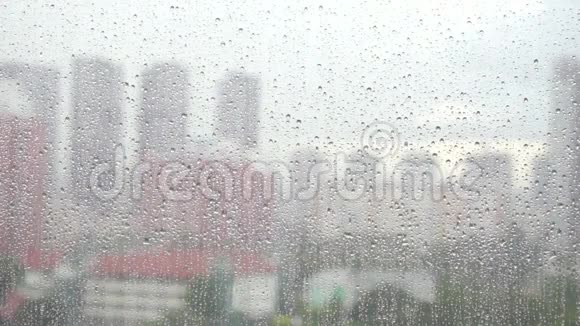 潮湿的窗户玻璃阴天模糊的城市背景下的窗户玻璃表面的雨滴视频的预览图
