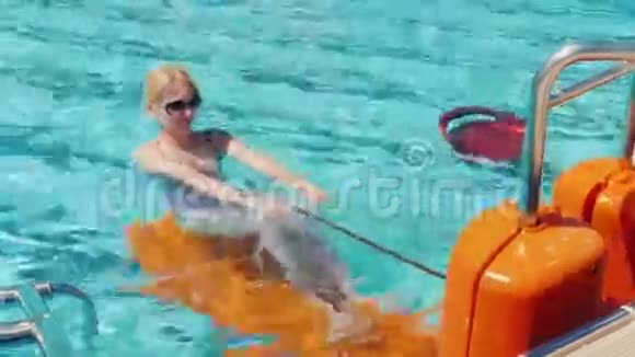 年轻女子正在游泳池里的模拟器上锻炼活跃在新鲜空气中休息在度假村活动视频的预览图