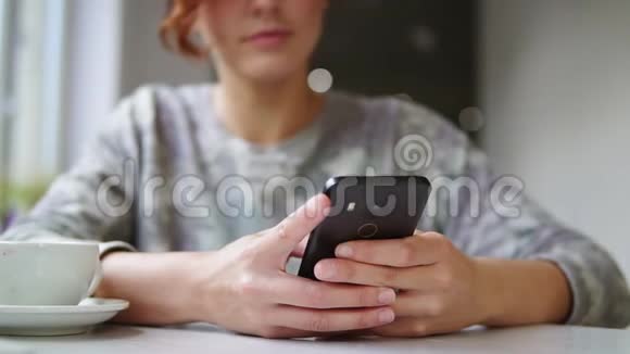 漂亮的年轻女性在咖啡馆里用手机微笑着在咖啡馆里使用智能手机的女人视频的预览图
