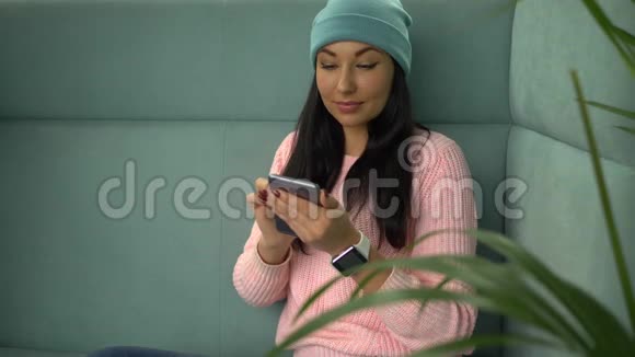 在咖啡馆里和朋友用手机聊天的混血时髦女人视频的预览图