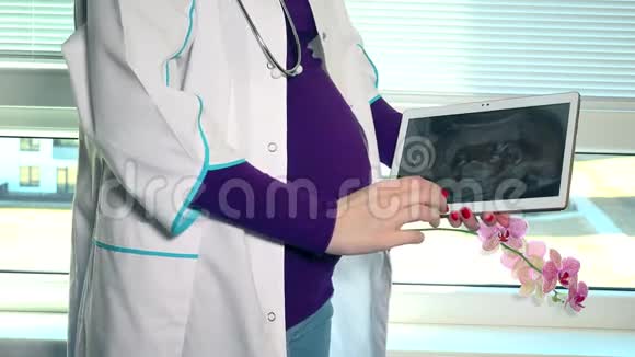 孕妇医生在平板电脑上显示她的超声波照片视频的预览图