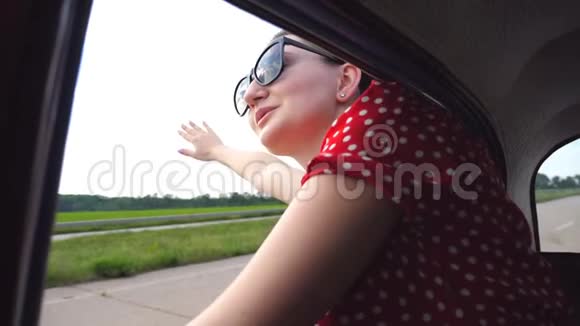 戴墨镜的快乐女孩斜倚在复古车窗外享受旅行有魅力的年轻女人看不动视频的预览图