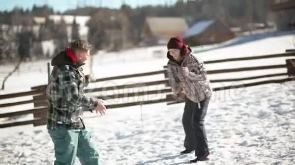 年轻夫妇正在打雪球男人和女人在冬天在外面玩得很开心侧面背景视频的预览图