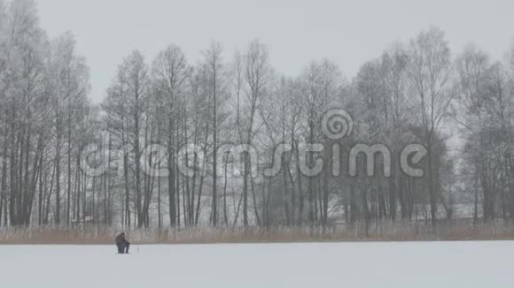 冬季捕鱼孤独的渔夫坐在冰上钓鱼视频的预览图