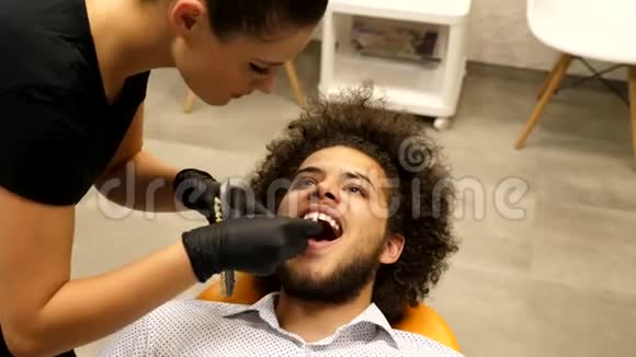 坐在牙医椅上等待牙医助手确定牙齿颜色的病人视频的预览图