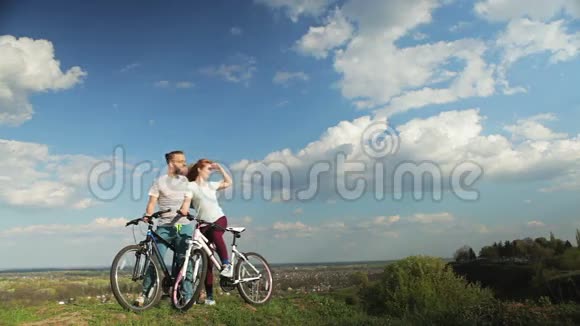 一对骑自行车的情侣站在高山上视频的预览图