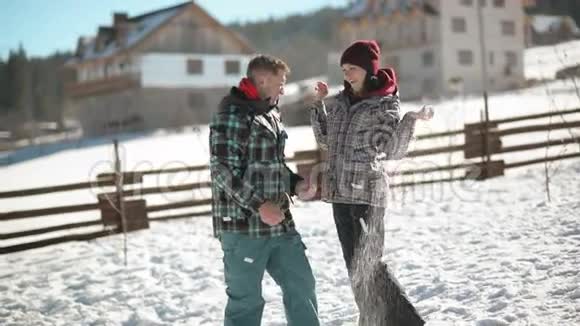 在温暖的冬天年轻的女人正在向她的男朋友扔雪年轻夫妇打雪仗视频的预览图