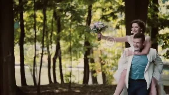 快乐的新郎背着笑着的新娘跑新婚快乐的一对夫妻视频的预览图