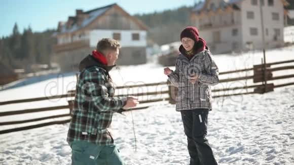 一个男人在温暖的冬天向他的女友扔雪年轻夫妇正在打雪球视频的预览图