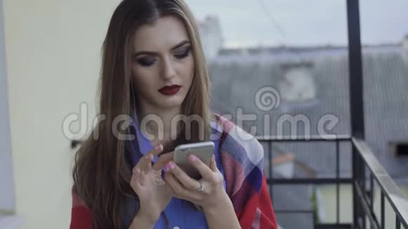 4K阳台上用智能手机化妆的漂亮女孩视频的预览图