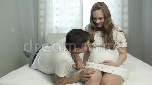 丈夫躺在怀孕的妻子膝盖上听着她肚子里的声音视频的预览图